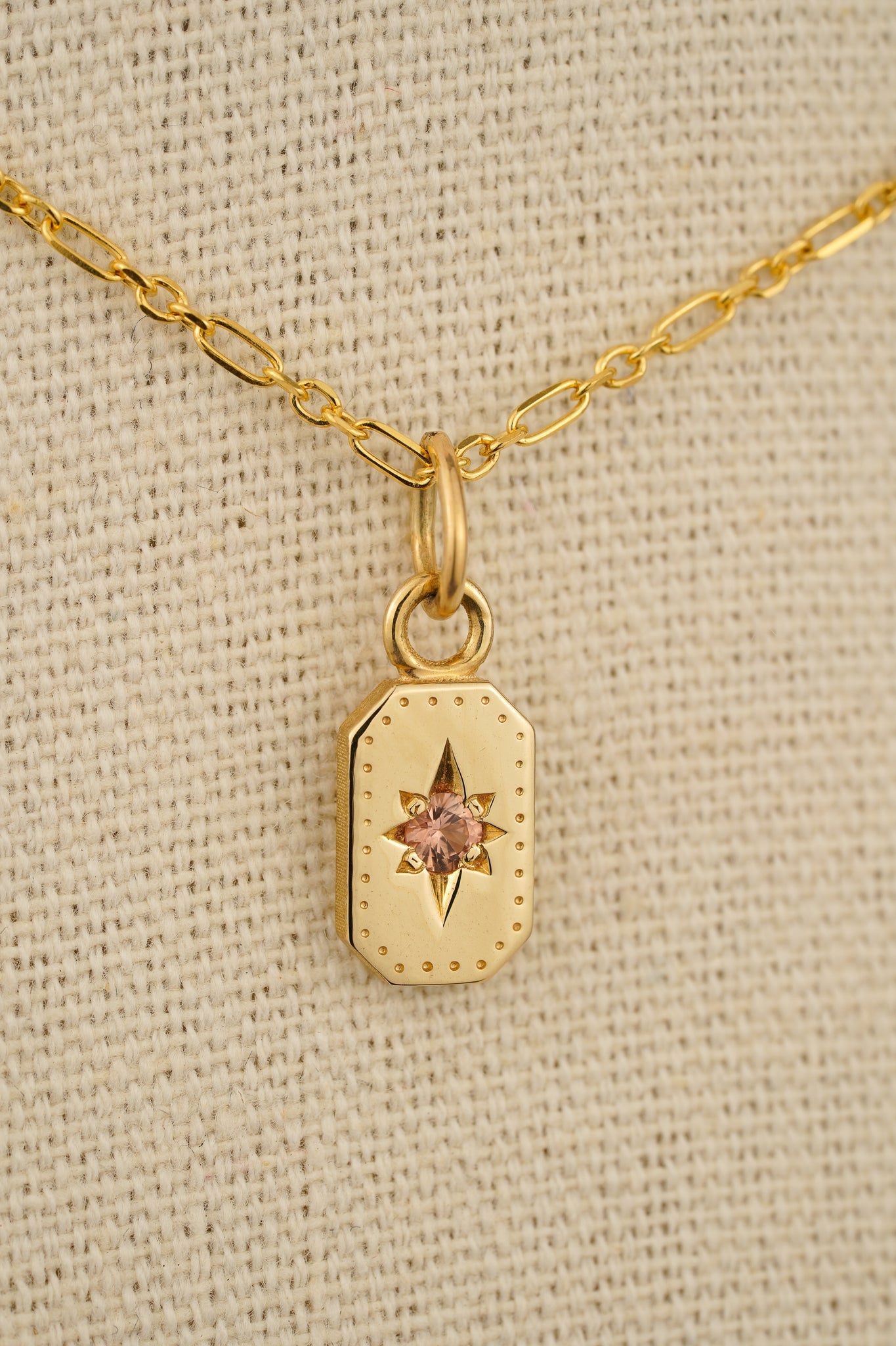 Solid gold emerald cut pendant with peach sapphire